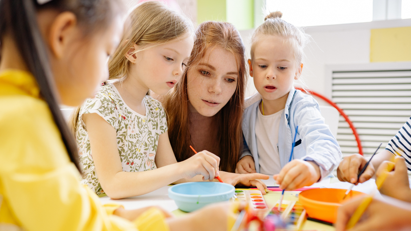 kindergarten teacher observing children crafting